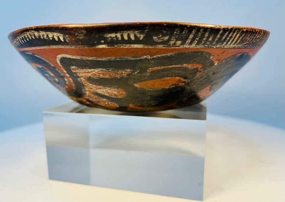 Side profile of ancient terracotta bowl with decorative scrolling patterns