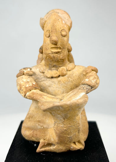 Hand-modeled ancient Mesoamerican terracotta drummer figure showing ear ornaments, drum, and earthen patina