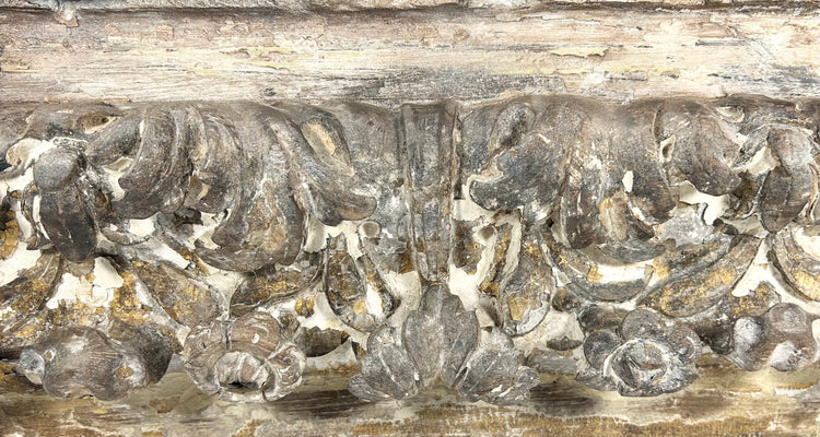 Rococo architectural wood carving with dramatic scrollwork, floral motifs, and worn gilding