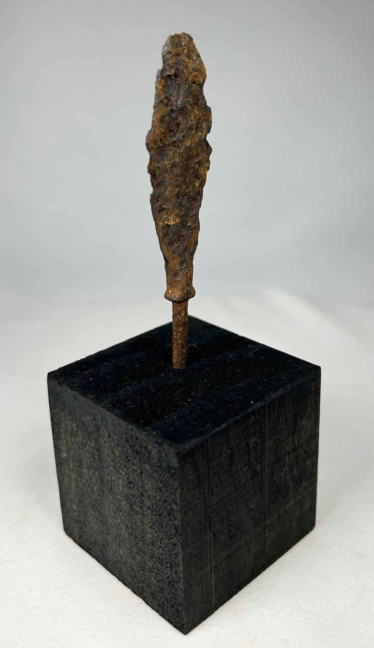 Authentic ancient forged iron projectile point photographed on museum-style stand