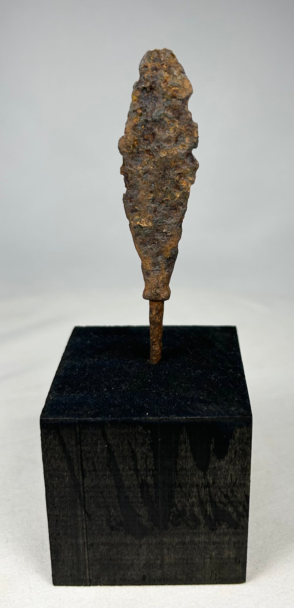 Close-up of corroded iron arrow or javelin tip with textured archaeological patina