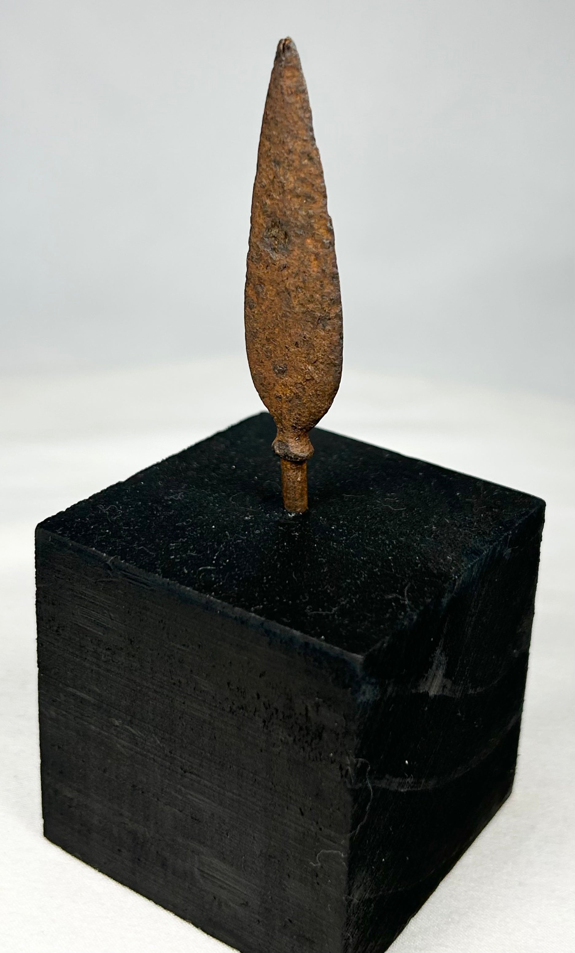 Close-up of ancient forged iron arrow tip showing natural corrosion and mineralization