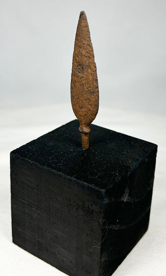 Close-up of ancient forged iron arrow tip showing natural corrosion and mineralization