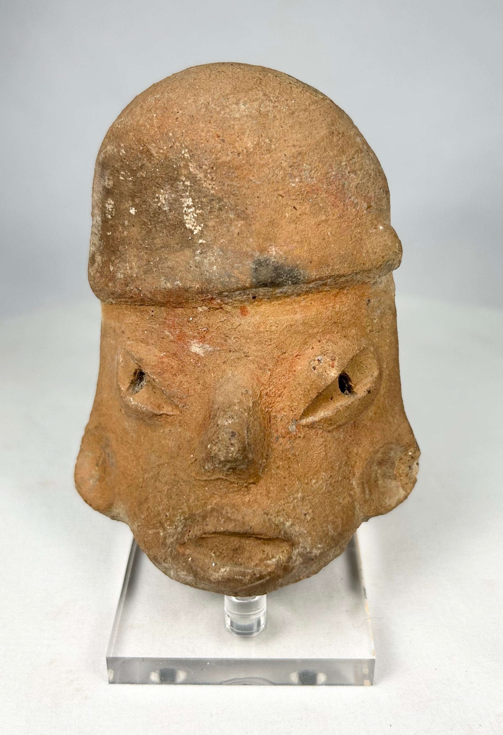 Hand-modeled Pre-Columbian terracotta head with almond-shaped eyes and pronounced brow, likely ritual in use.