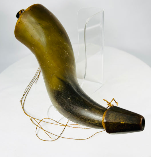 Curved horn powder vessel displayed on clear museum-style stand