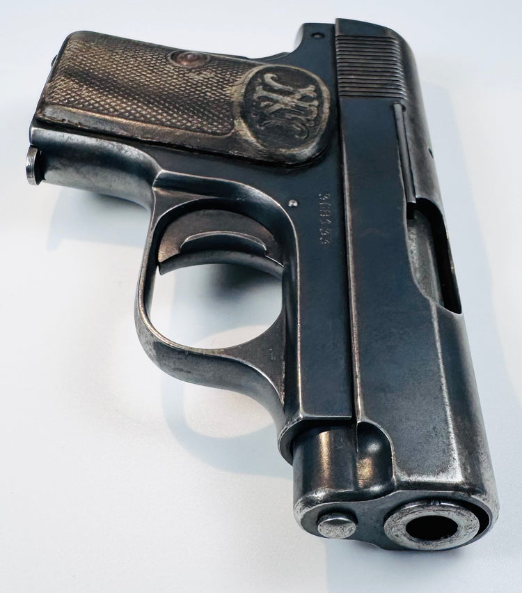 FN Browning Model 1906 highlighting the barrel opening, rounded steel contours, and wear along the textured grip.