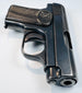 FN Browning Model 1906 highlighting the barrel opening, rounded steel contours, and wear along the textured grip.
