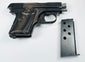 Browning Model 1906 pocket pistol beside a detached metal magazine with circular inspection holes.