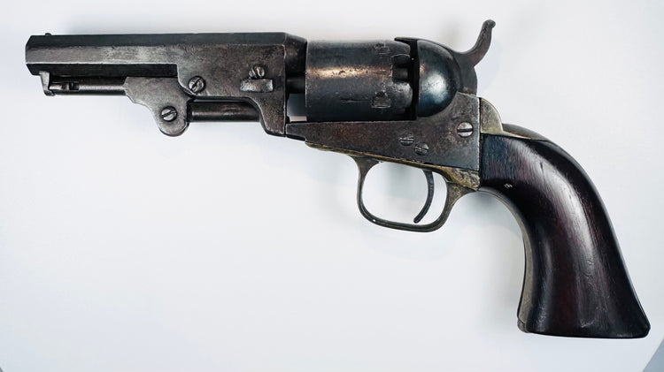 Colt Model 1849 Pocket Revolver with a four-inch octagonal barrel, five-shot cylinder, and curved walnut grip.