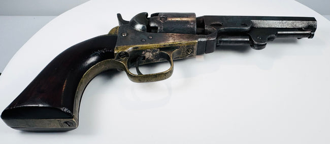 Colt Model 1849 Pocket Revolver highlighting the brass backstrap, rounded walnut grip base, and loading lever beneath the barrel.