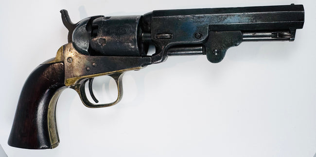 Colt Model 1849 Pocket Revolver with its loading lever folded beneath the barrel and brass fittings bordering the walnut grip.