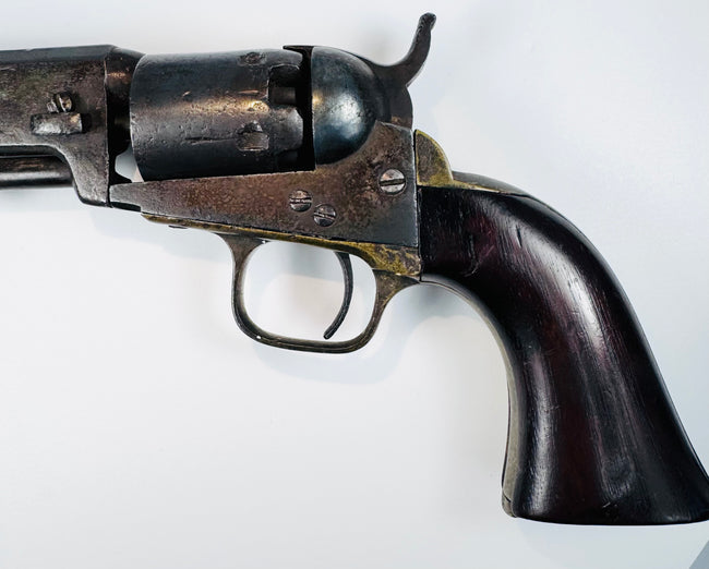 Colt Model 1849 Pocket Revolver detail showing the cylinder and exposed hammer above the brass trigger guard and walnut grip.