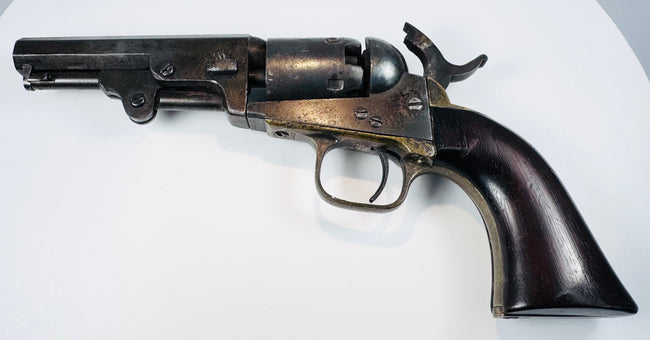 Colt Model 1849 Pocket Revolver with a smooth walnut grip, aged brass backstrap, and dark steel barrel and cylinder.