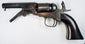 Colt Model 1849 Pocket Revolver with its loading lever lowered beneath the octagonal barrel and its curved walnut grip visible.