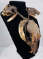 Skull necklace with two smaller skulls along the braided cord and long, tapered teeth suspended beneath them.