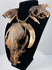 Animal skull necklace highlighting the central skull’s elongated muzzle, open eye socket, and surrounding twine bindings.