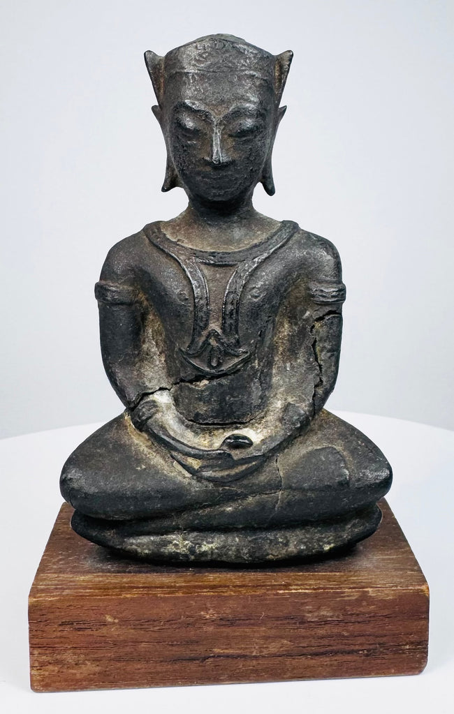 Bronze Buddha statue with a calm expression, winged crown ornaments, and lighter surface wear across its dark patina.