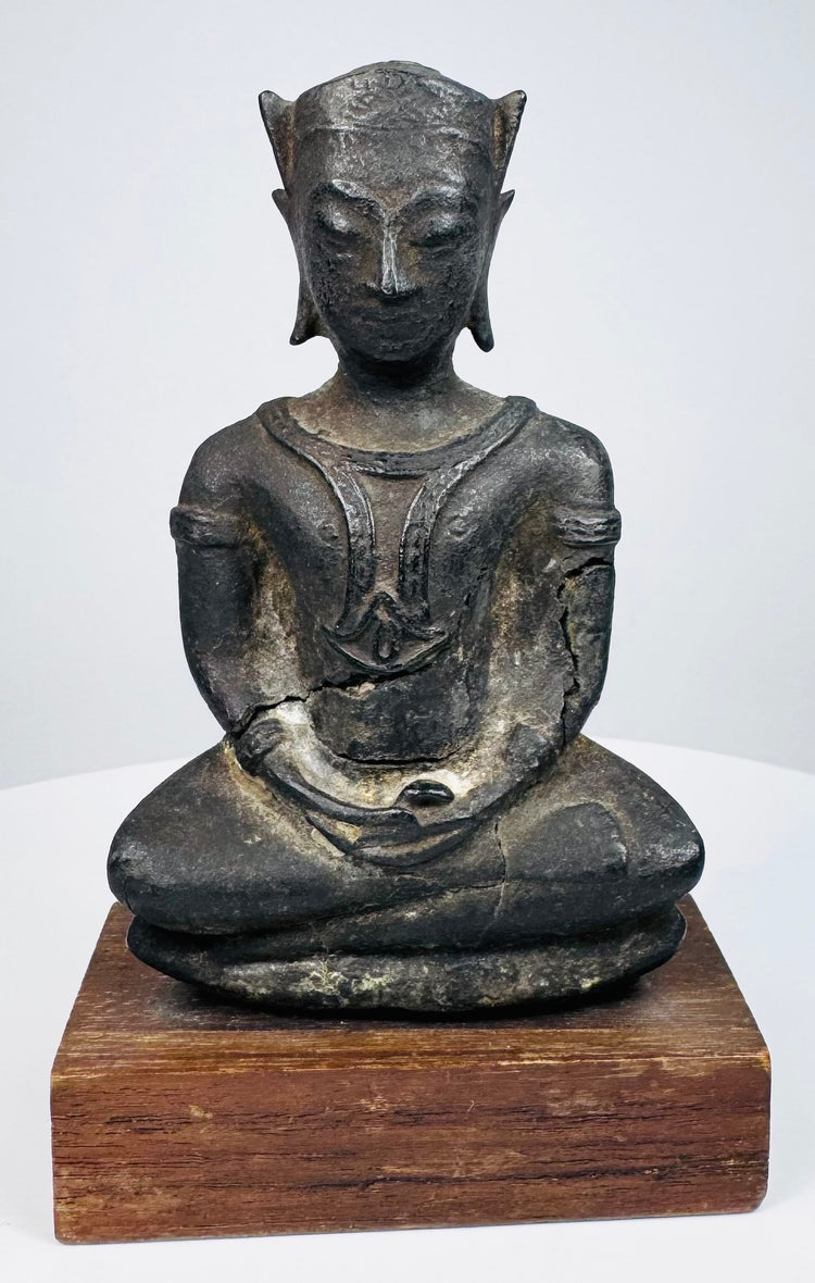 Bronze Buddha statue with a calm expression, winged crown ornaments, and lighter surface wear across its dark patina.