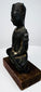 Bronze Buddha highlighting elongated ear ornaments, a slender torso, and crossed legs resting on a low bronze plinth.