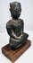 Seated bronze Buddha showing layered chest ornamentation, hands resting in its lap, and lighter wear along the arms.