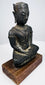 Seated bronze Buddha showing layered chest ornamentation, hands resting in its lap, and lighter wear along the arms.