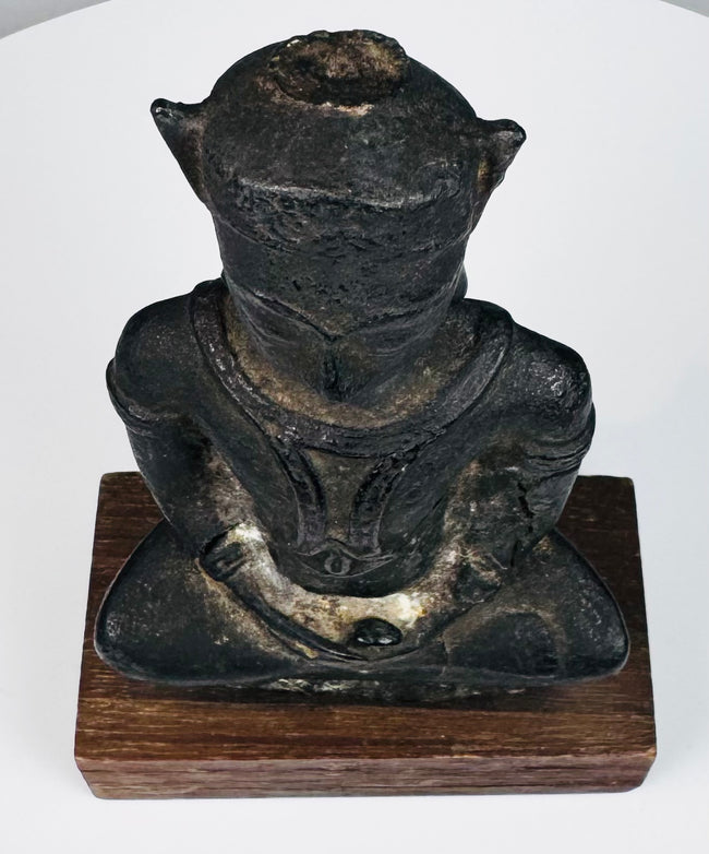 Bronze Buddha highlighting the textured crown, symmetrical ear ornaments, folded hands, and crossed legs beneath its torso.