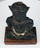 Bronze Buddha highlighting the textured crown, symmetrical ear ornaments, folded hands, and crossed legs beneath its torso.