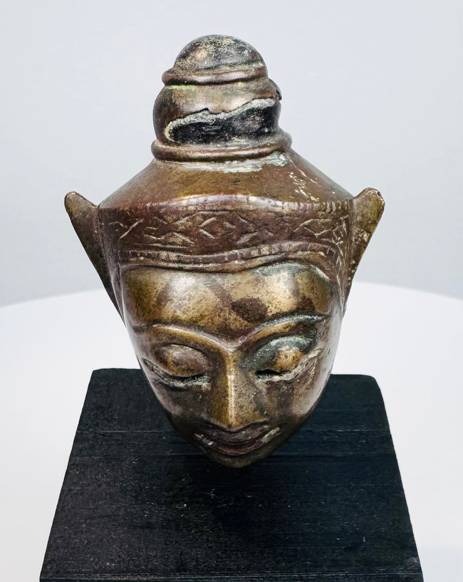 Antique Southeast Asian Buddha head sculpture with serene face, elongated ears, and decorative crown