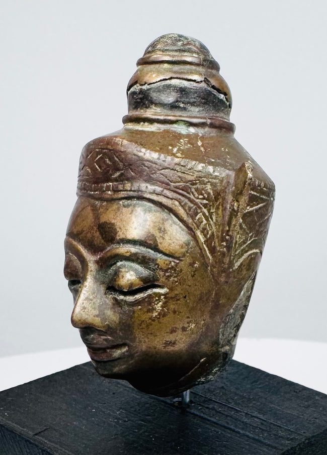 Antique Buddha head with half-closed eyes, slender nose, and detailed crown ornamentation