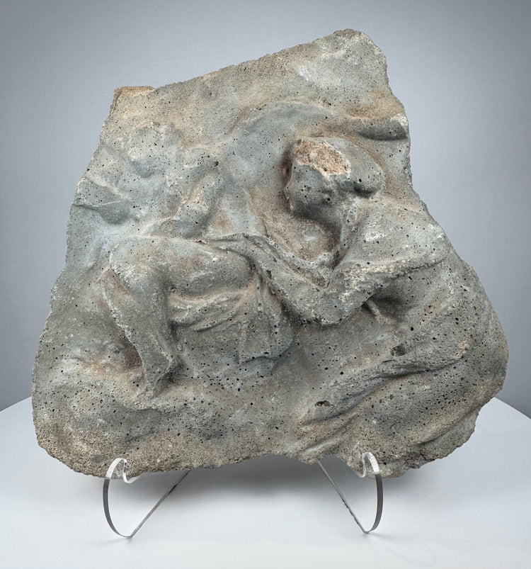 Ancient Roman carved stone relief depicting two Classical figures in deeply weathered volcanic tuff