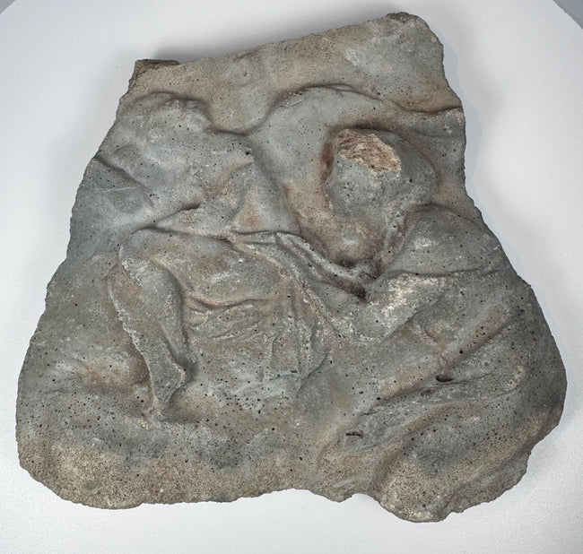 Roman volcanic tuff fragment with raised figural carving, irregular ancient-style edges and aged surface deposits