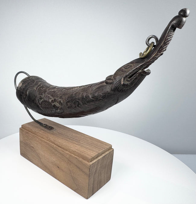 Carved Tibetan ceremonial horn with curved body, dark natural patina, and symbolic makara head at the tip.