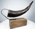 Angled view of a Tibetan carved horn ritual implement with decorative body motifs and opening for ritual use.