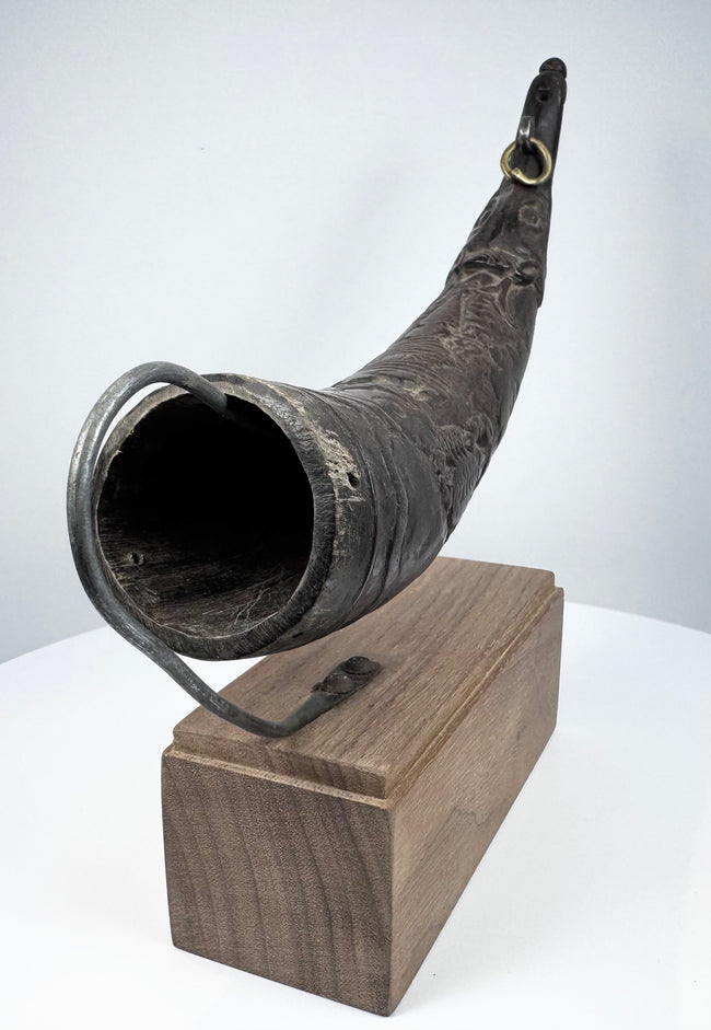 Close view of an antique Tibetan Buddhist horn displaying its curved profile, carved details, and natural aged surface.