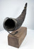 Close view of an antique Tibetan Buddhist horn displaying its curved profile, carved details, and natural aged surface.