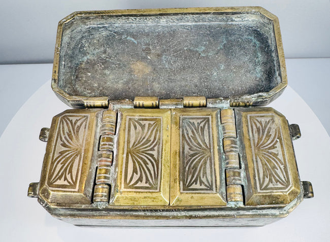 Interior of an antique Mindanao buyo box showing four decorated compartment lids arranged within the fitted metal case.