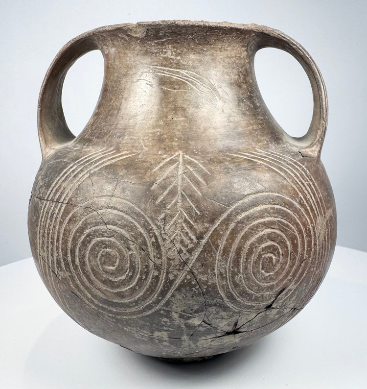 Ancient Etruscan terracotta amphora showing its rounded body, high loop handles, short neck, and dark impasto surface.