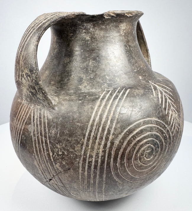 Early Etruscan amphora showing both handles, broad shoulder, and radiating geometric decoration between the large spiral motifs.