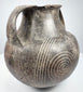 Early Etruscan amphora showing both handles, broad shoulder, and radiating geometric decoration between the large spiral motifs.