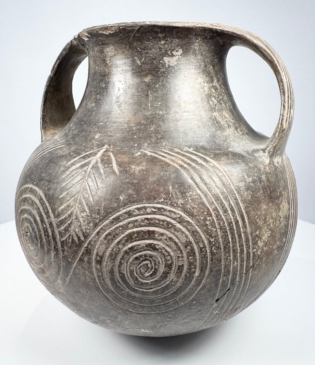 Upper angle of the Etruscan impasto vessel showing the open mouth, thick rim, twin handles, and incised decoration across the shoulder.
