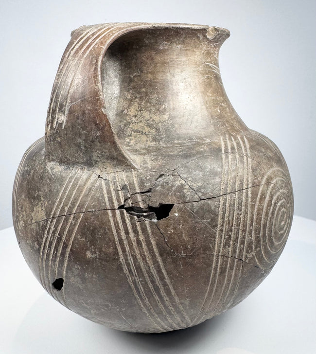 Side of the ancient Etruscan amphora showing one prominent loop handle and spiral ornament continuing around the rounded body.