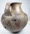 Side of the ancient Etruscan amphora showing one prominent loop handle and spiral ornament continuing around the rounded body.