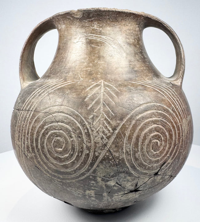 Opposite side of the impasto amphora with one handle prominent and concentric spirals extending across the lower body.