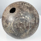 Ancient impasto amphora showing a side section with linear incisions, aged terracotta surface, and a visible vertical crack on the body.