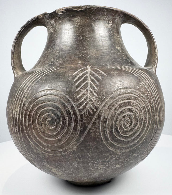 Etruscan spiral amphora with both loop handles visible and two large concentric spiral motifs dominating the darker ancient surface.