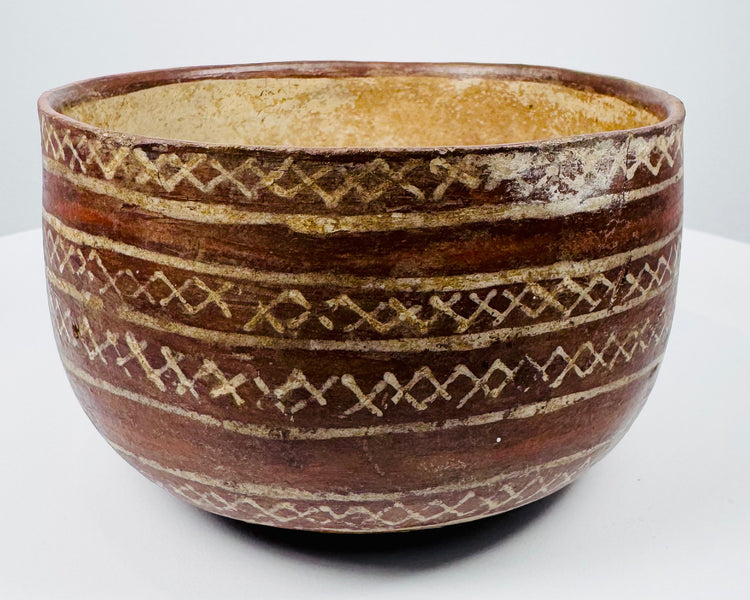 Decorated earthenware bowl with repeating X-shaped motifs and a pale buff interior.
