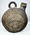 Dark-fired ceramic canteen with raised human face and feather-like ornament