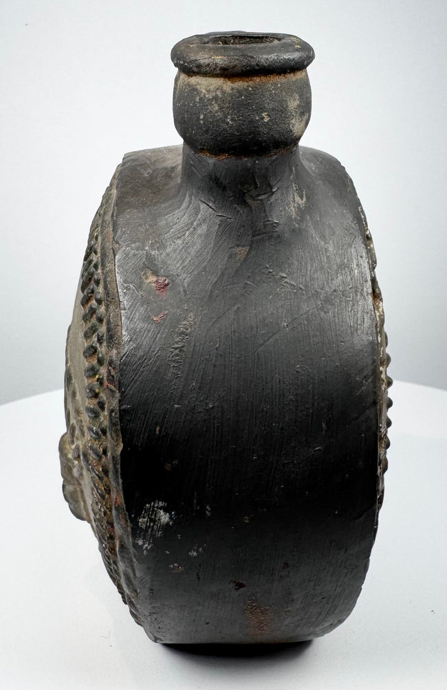 Pre-Columbian ceramic flask with stepped border surrounding a modeled face