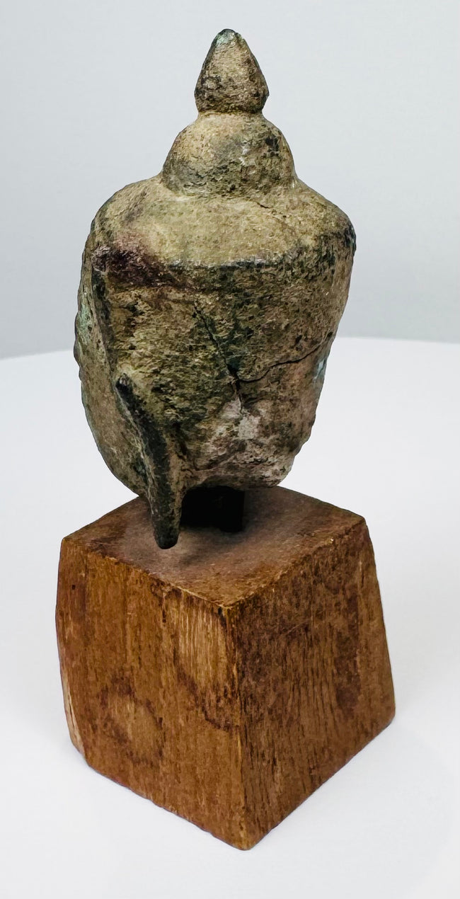 Ancient Thai Buddha head with downcast eyes, elongated face and extensive natural surface encrustation