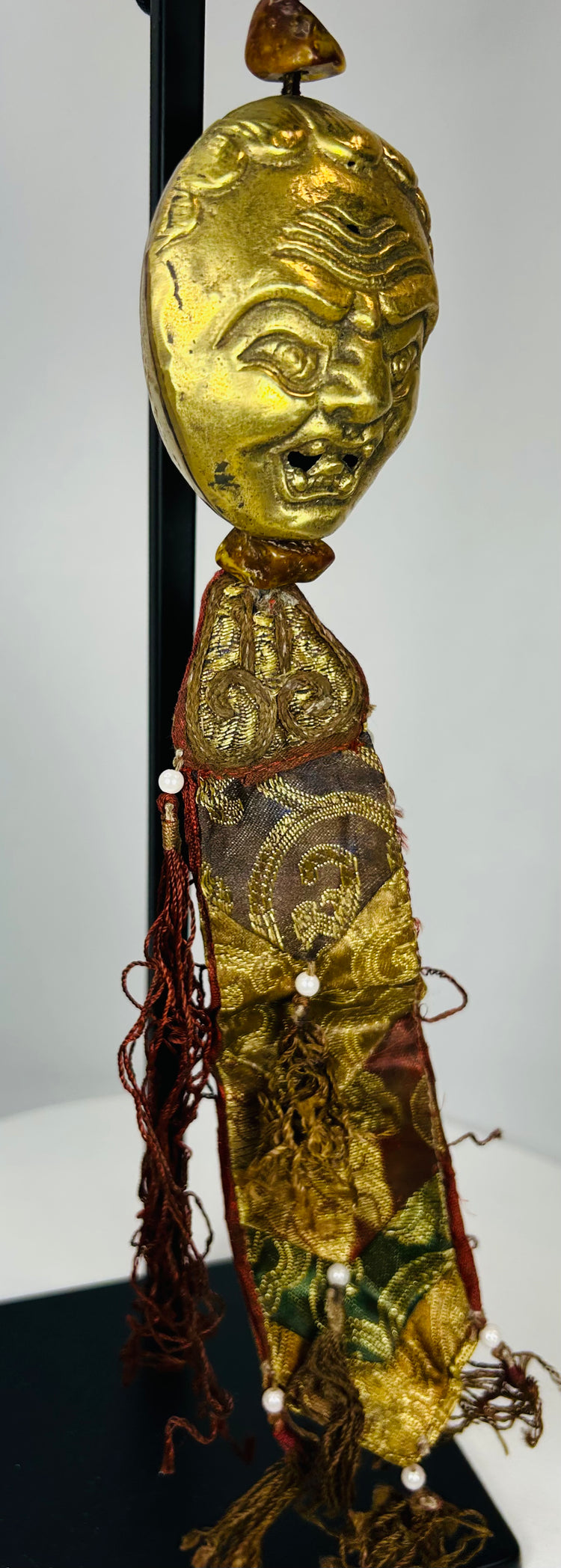 Tibetan ritual pendant with gilt bronze mask and aged textiles